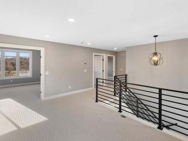 carpeted spare room featuring an inviting chandelier