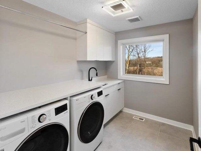 laundry room featuring sink, cabinets, washing machine and dryer, a textured ceiling, and light tile patterned flooring