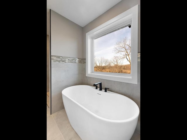 bathroom featuring a bathtub, tile walls, and tile patterned flooring