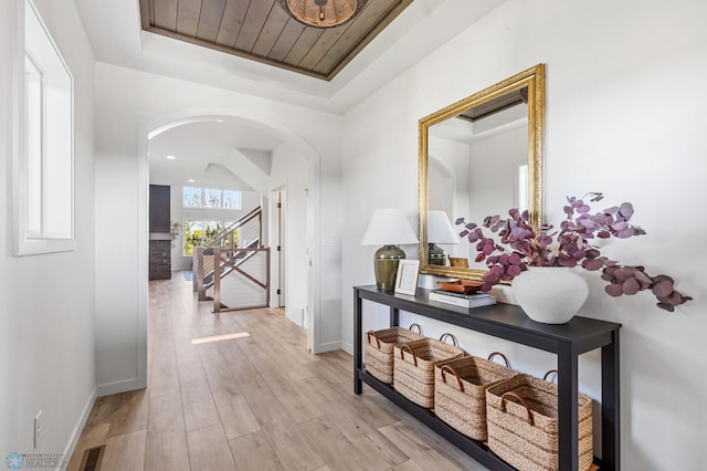 hall featuring light hardwood / wood-style floors and a raised ceiling