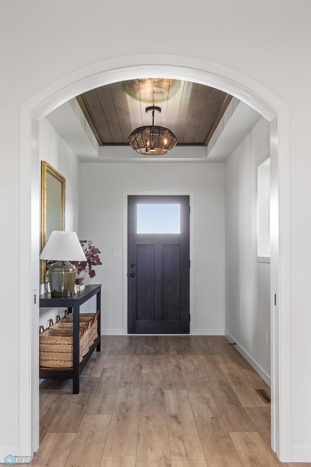 entryway featuring a raised ceiling and light hardwood / wood-style floors