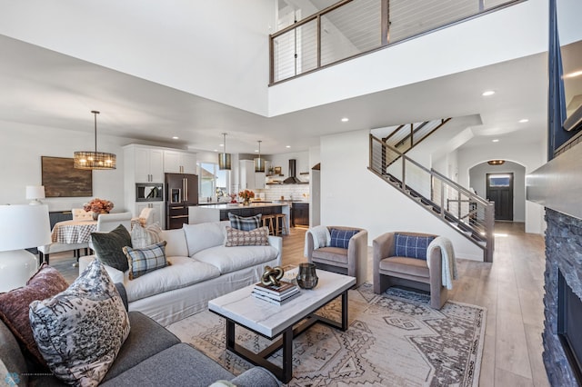 living room with an inviting chandelier, light hardwood / wood-style flooring, and a high ceiling