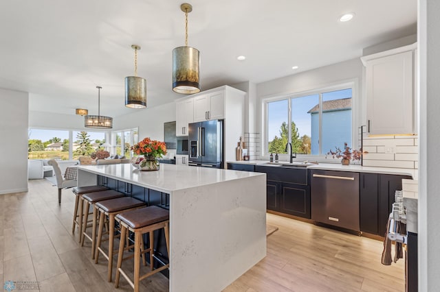 kitchen with white cabinetry, decorative light fixtures, a kitchen island, and appliances with stainless steel finishes