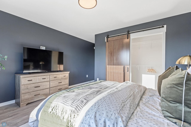 bedroom with a barn door, a closet, and light hardwood / wood-style flooring