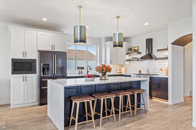 kitchen with white cabinetry, pendant lighting, a center island, and black appliances