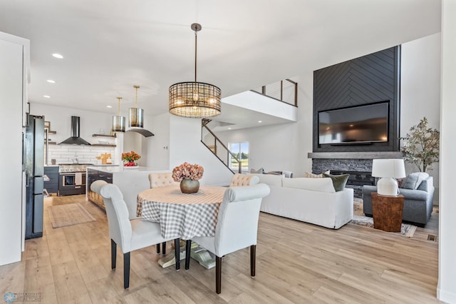 dining space with a stone fireplace, light hardwood / wood-style floors, and a notable chandelier