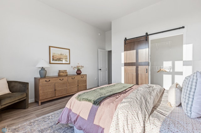 bedroom with a closet, light hardwood / wood-style flooring, and a barn door