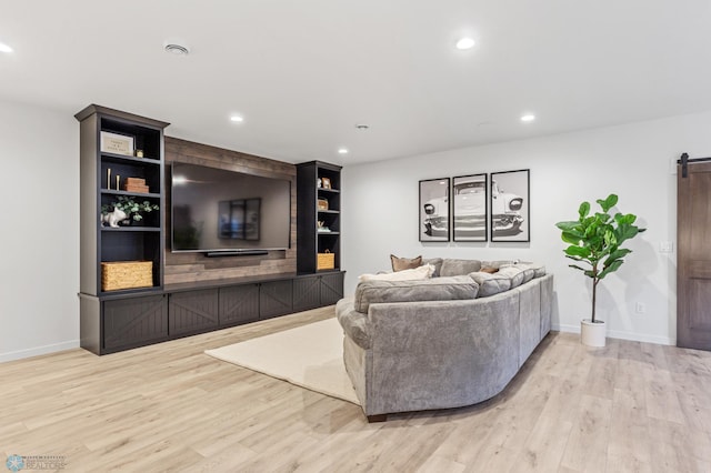 living room with a barn door and light wood-type flooring