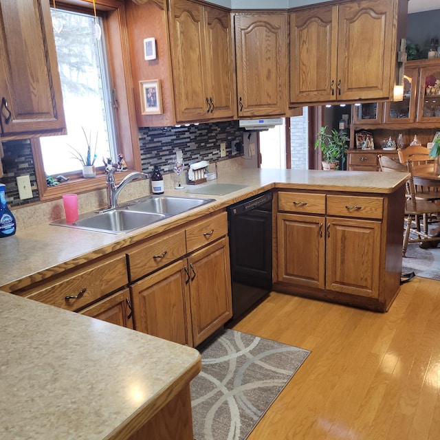 kitchen with kitchen peninsula, tasteful backsplash, sink, dishwasher, and light hardwood / wood-style floors