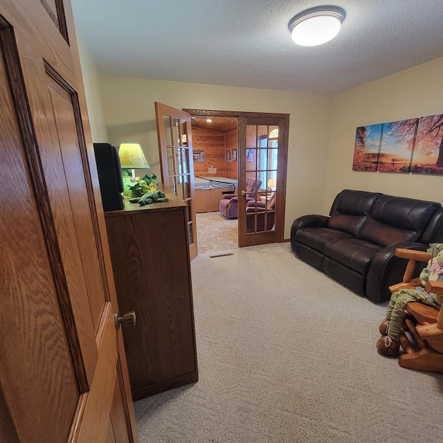 living room featuring french doors, light colored carpet, and a textured ceiling