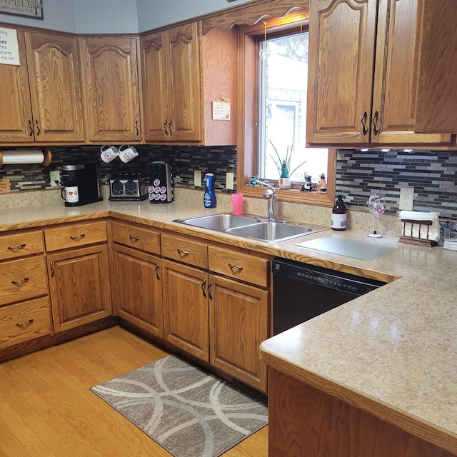 kitchen with brown cabinetry, light countertops, a sink, and dishwasher