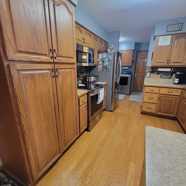 kitchen with brown cabinets, light wood finished floors, appliances with stainless steel finishes, and light countertops