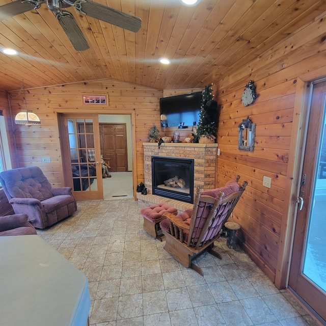 living area with wooden walls, wood ceiling, vaulted ceiling, french doors, and a fireplace