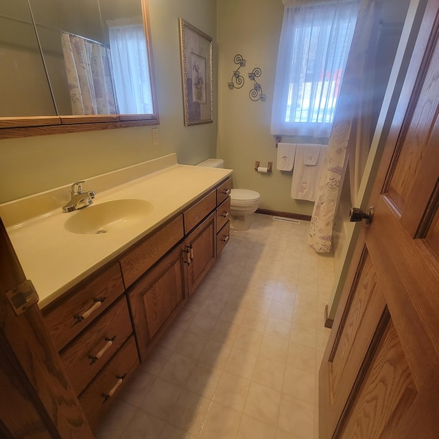 bathroom with toilet, tile patterned floors, baseboards, and vanity