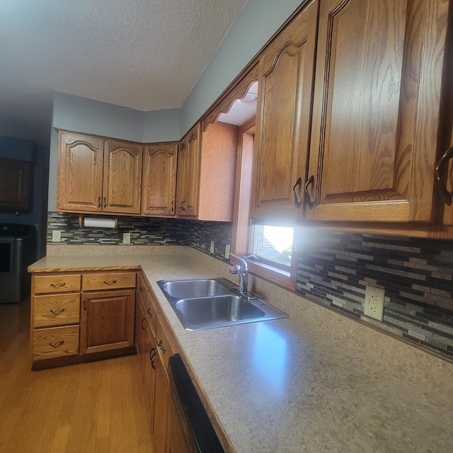 kitchen featuring brown cabinets, tasteful backsplash, washer / clothes dryer, light countertops, and a sink