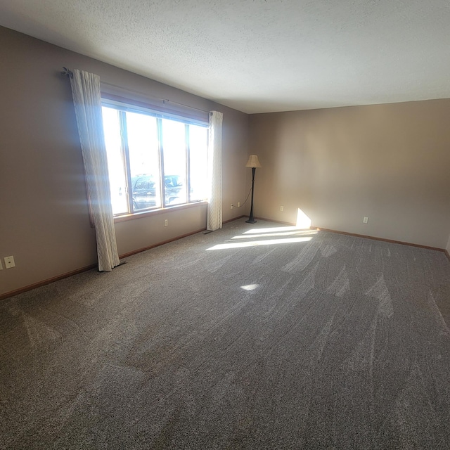 carpeted spare room with a textured ceiling and baseboards