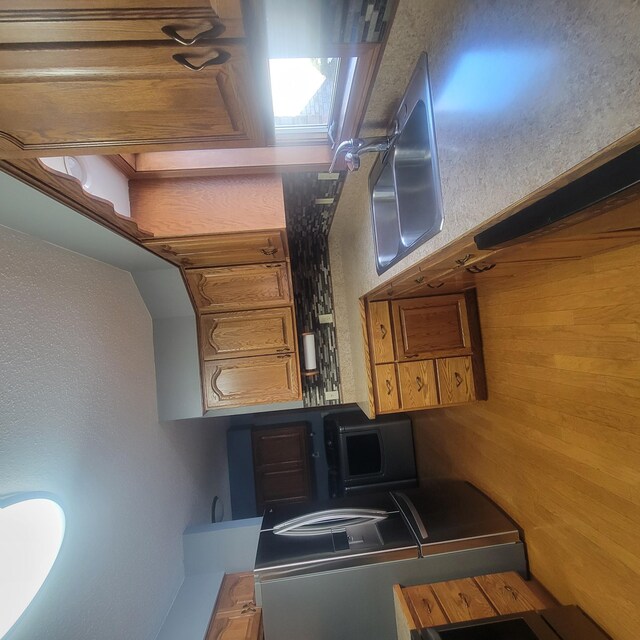 kitchen featuring washer / clothes dryer, brown cabinets, and a sink