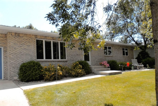 view of home's exterior with brick siding and a lawn