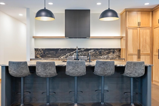 kitchen with light stone counters, a breakfast bar, and hanging light fixtures