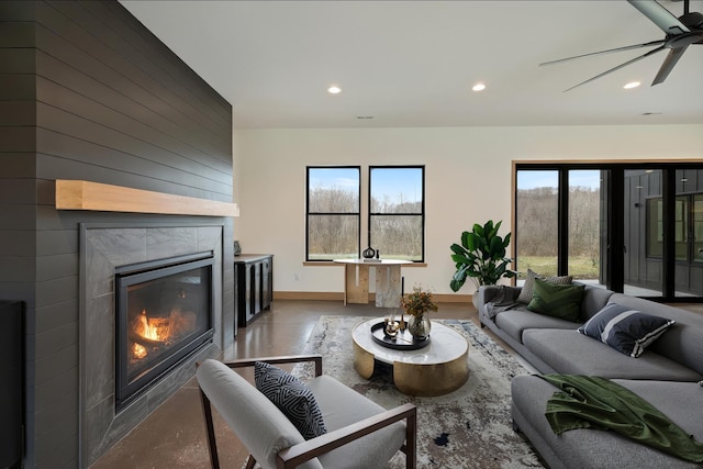 living area with recessed lighting, baseboards, a ceiling fan, and a fireplace