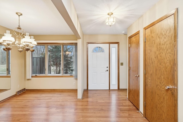 foyer entrance with light hardwood / wood-style flooring and an inviting chandelier