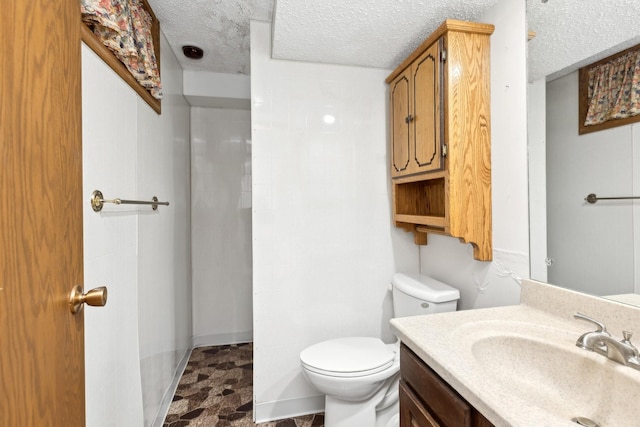 bathroom with vanity, toilet, and a textured ceiling