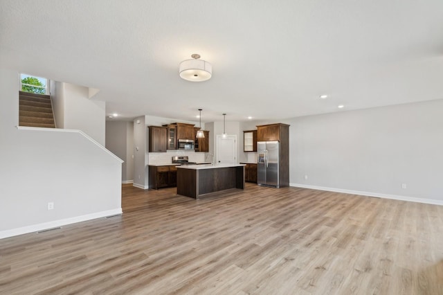 kitchen featuring a center island, light countertops, hanging light fixtures, appliances with stainless steel finishes, and open floor plan