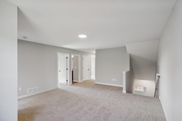 interior space featuring baseboards, visible vents, and light colored carpet