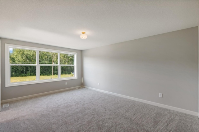 empty room with carpet floors, visible vents, and baseboards