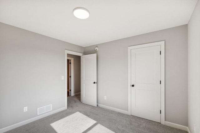 unfurnished bedroom featuring visible vents, light carpet, and baseboards