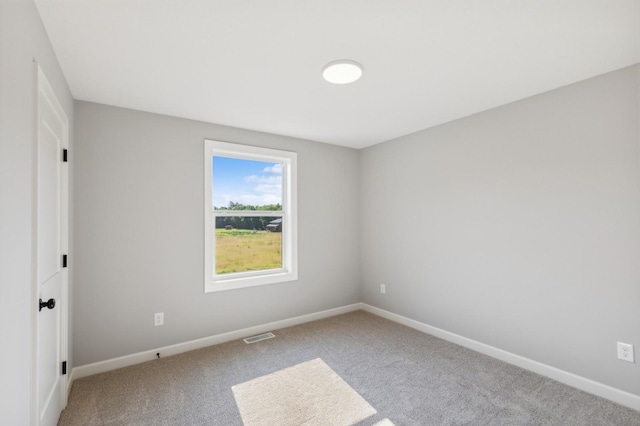 spare room with carpet floors, visible vents, and baseboards