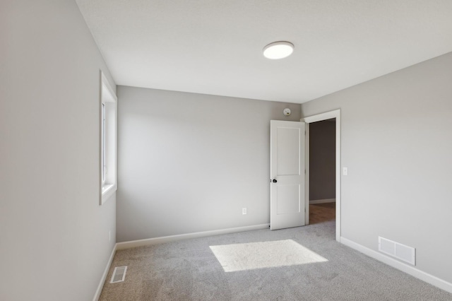 unfurnished room featuring light colored carpet, visible vents, and baseboards