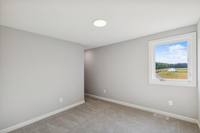 spare room featuring baseboards, visible vents, and light colored carpet