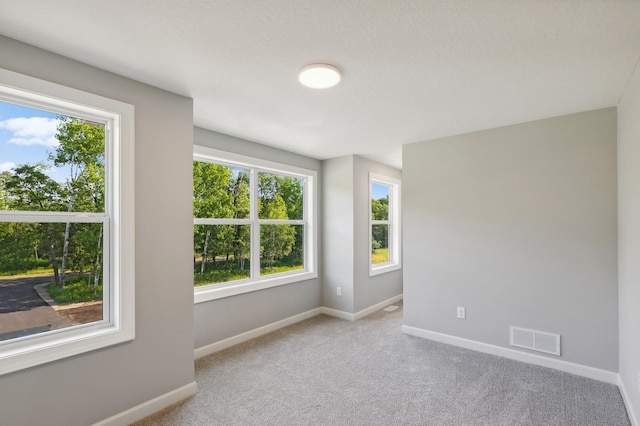 unfurnished room with visible vents, light carpet, and baseboards