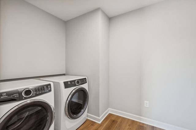 laundry room with laundry area, baseboards, washer and clothes dryer, and wood finished floors