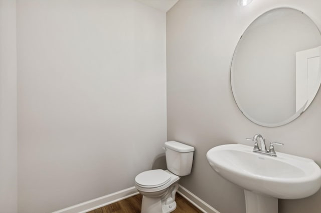 bathroom featuring a sink, wood finished floors, toilet, and baseboards