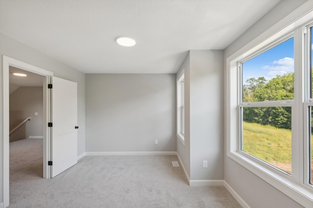 spare room featuring light carpet and baseboards