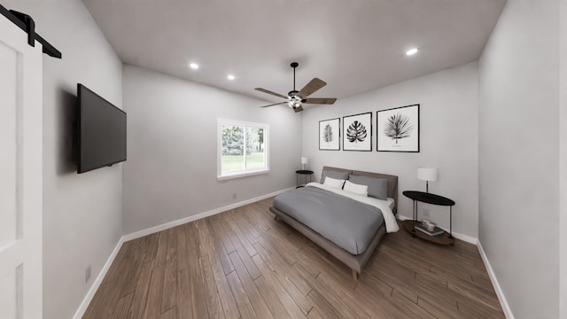 bedroom with hardwood / wood-style flooring, ceiling fan, and a barn door