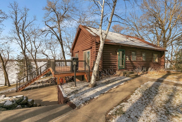 view of home's exterior with a deck, log siding, stairs, and a shingled roof