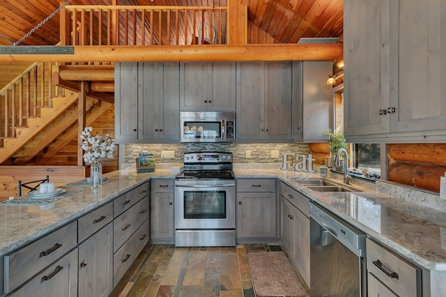 kitchen featuring a sink, gray cabinetry, vaulted ceiling, appliances with stainless steel finishes, and tasteful backsplash