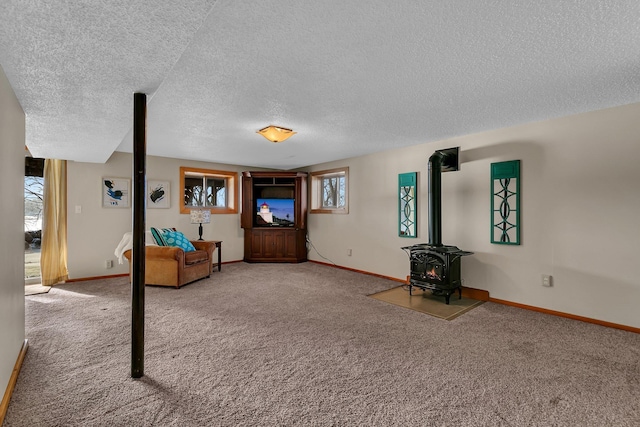 unfurnished living room featuring a wood stove, carpet flooring, and baseboards