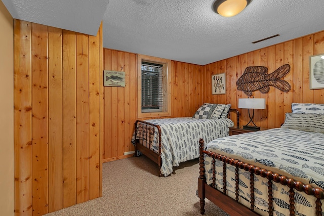 bedroom featuring wooden walls, carpet floors, and a textured ceiling