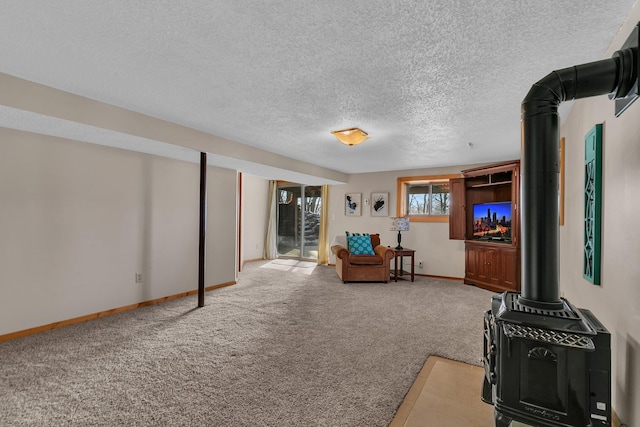 sitting room featuring a wood stove, carpet, baseboards, and a textured ceiling