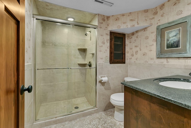 full bath featuring visible vents, wallpapered walls, toilet, wainscoting, and a stall shower