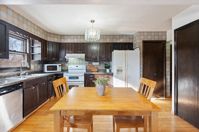 kitchen featuring white appliances, a textured ceiling, hanging light fixtures, dark brown cabinets, and sink