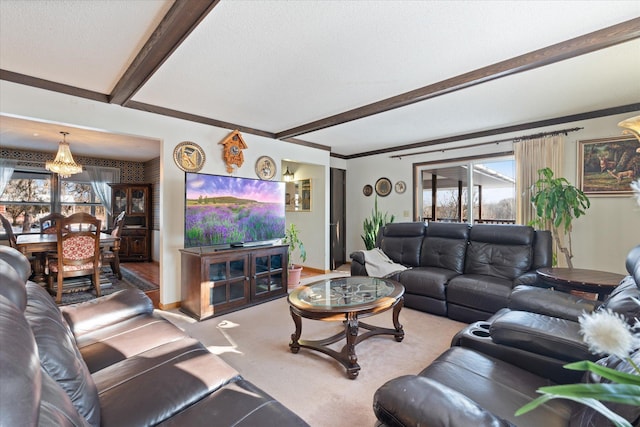 carpeted living room with a textured ceiling, beam ceiling, and a chandelier