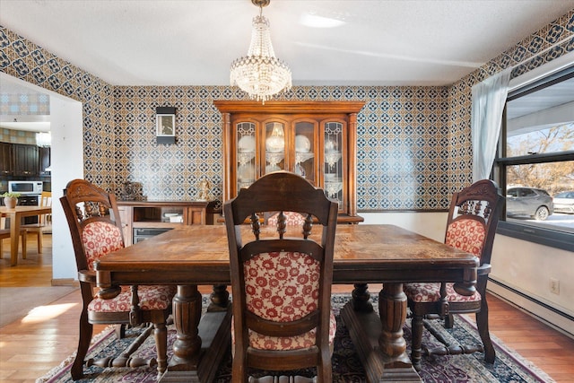 dining space featuring a notable chandelier, a baseboard radiator, and wood-type flooring