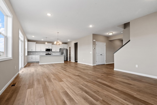 unfurnished living room with a chandelier, light wood-type flooring, and sink