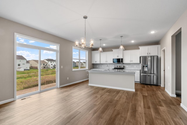 kitchen featuring appliances with stainless steel finishes, decorative light fixtures, white cabinetry, and dark wood-type flooring