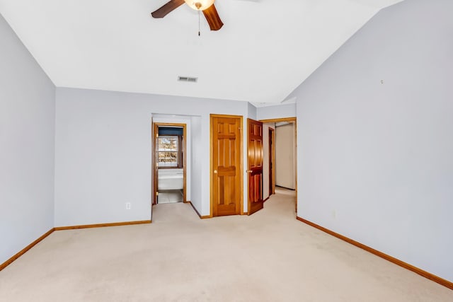 unfurnished bedroom with ceiling fan, ensuite bath, light carpet, and vaulted ceiling